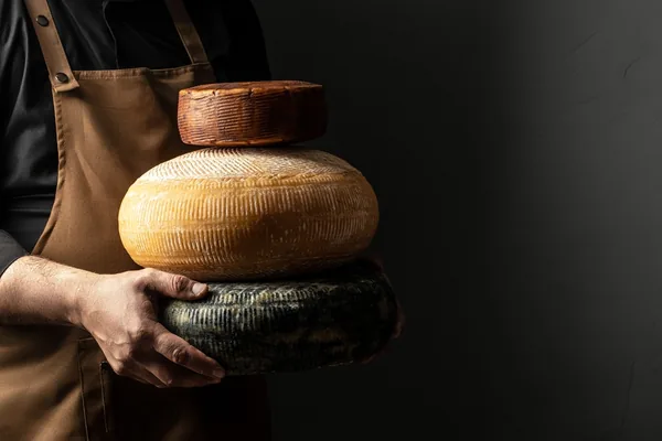 Verschillende gerijpte kazen gedragen door een kaasmaker